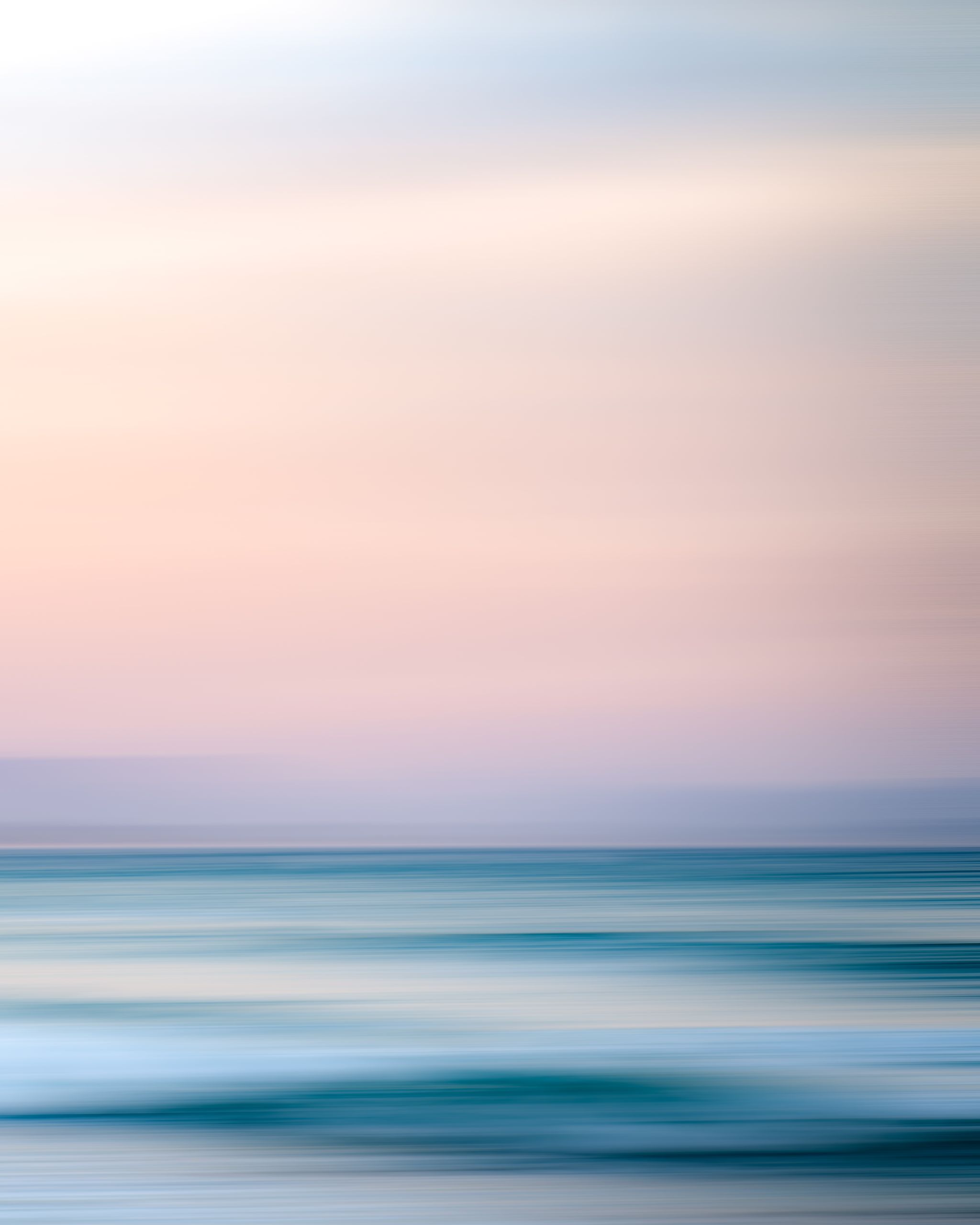 Long exposure of wonderful scenery of turquoise sea located beneath light pink sky in early evening
